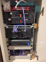 Photo of a small white wooden cabinet. It's open and contains many small computers, mounted in casings between two metal rails