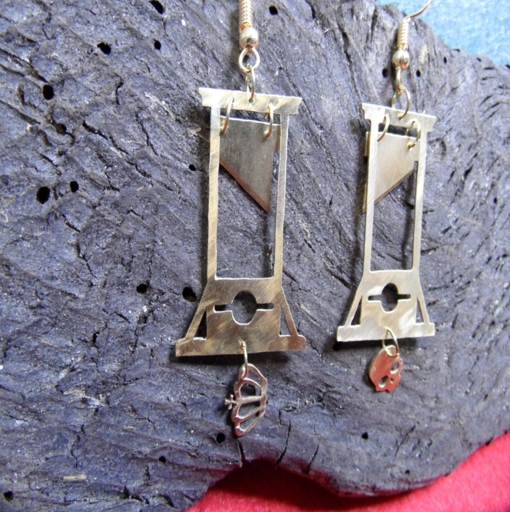 Brass guillotine earrings made from a thin brass plate, one with a crown and one with a skull dangling underneath.